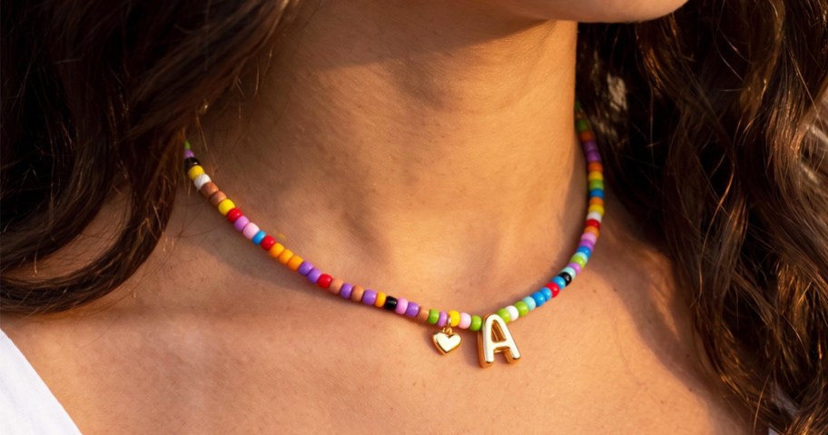 woman wearing colorful beaded necklace with gold letter A pendant