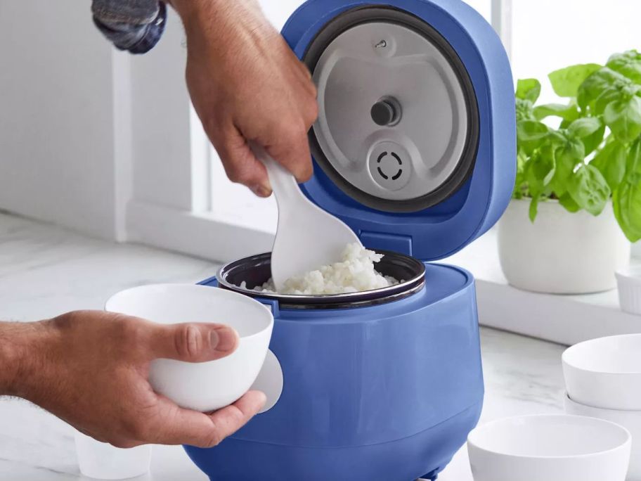 Hand using a spooon to scoop rice from a GreenLife Rice Cooker