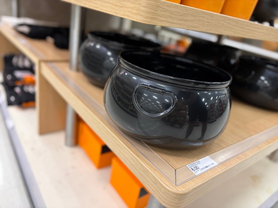 A black Hyde & EEK! large Halloween cauldron serving bowl displayed on a store shelf.