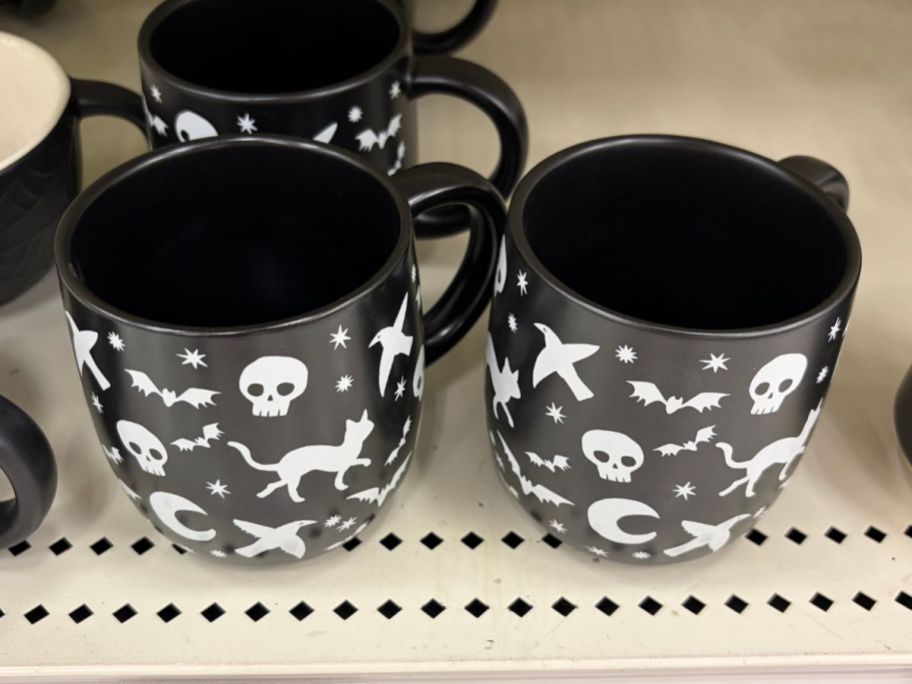 Hyde & EEK! Boutique Stoneware Black Decal Skulls/Cats/Bats Mugs on shelf in store