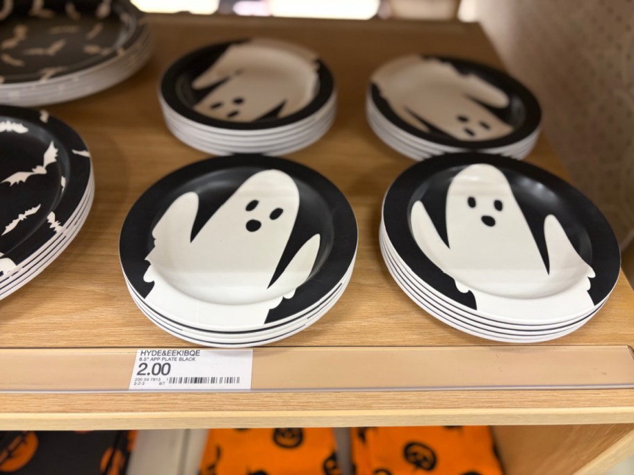 Stacks of black and white Hyde & EEK! Halloween melamine appetizer plates featuring a friendly ghost design displayed on a store shelf.