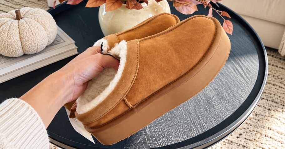 hand holding up a pair of tan platform clog slippers