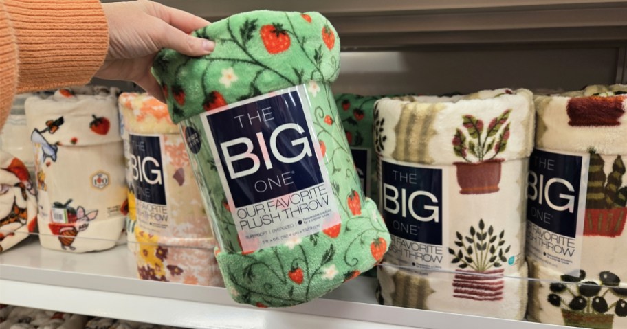 hand holding up a strawberry print blanket in store
