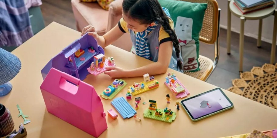 girl building lego suitcase set on table
