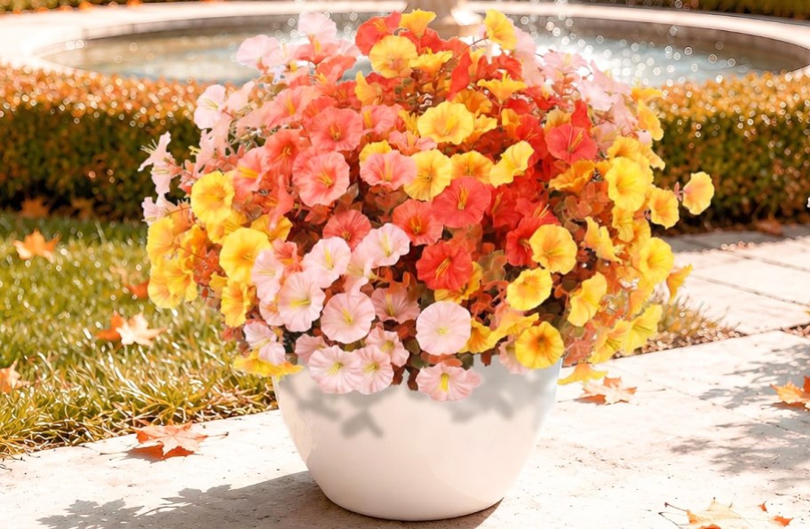 pink, orange, and yellow artificial flowers in a white pot