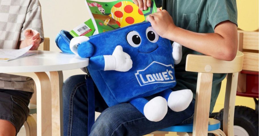 kid holding Lowe's Plush Bucket Backpack in classroom