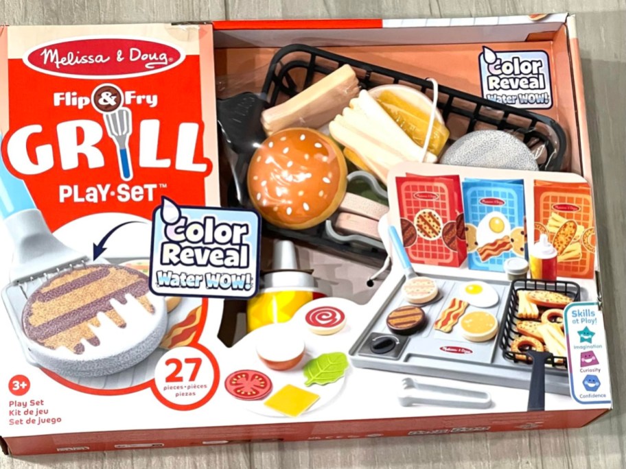 Melissa & Doug Flip & Fry Grill Play Set boxed toy featuring 27 pieces of play food, a grill toy, and color-reveal water wow features.