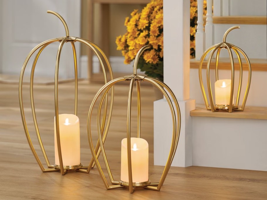 set of three gold wired pumpkins with candles in center on floor and stairs