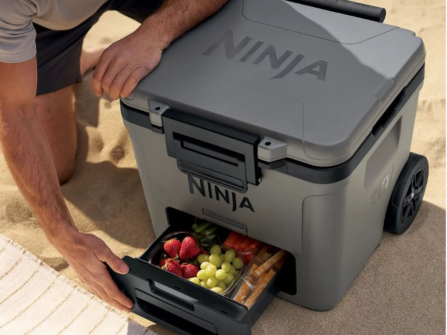 Man with a Ninja FrostVault 30qt Wheeled Cooler w/ Dry Zone drawer open filled with food