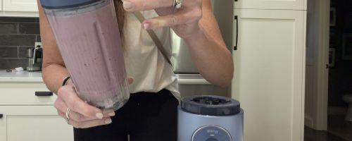 Woman holding a Ninja MAXX blender in her kitchen