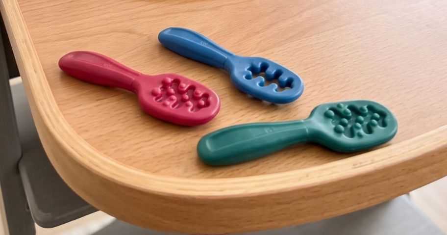 three NumNum Feeding Littles Baby Spoons on high chair