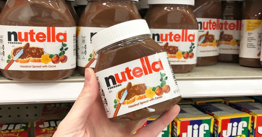 A hand holding a jar of Nutella in a store