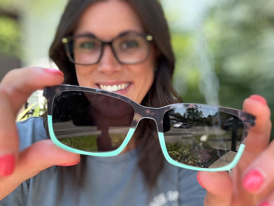woman holding up a pair of sunglasses toppers