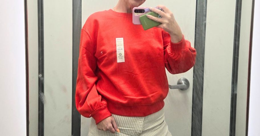 stefanie wearing orange Scenario Women's Crewneck Sweatshirt in store fitting room