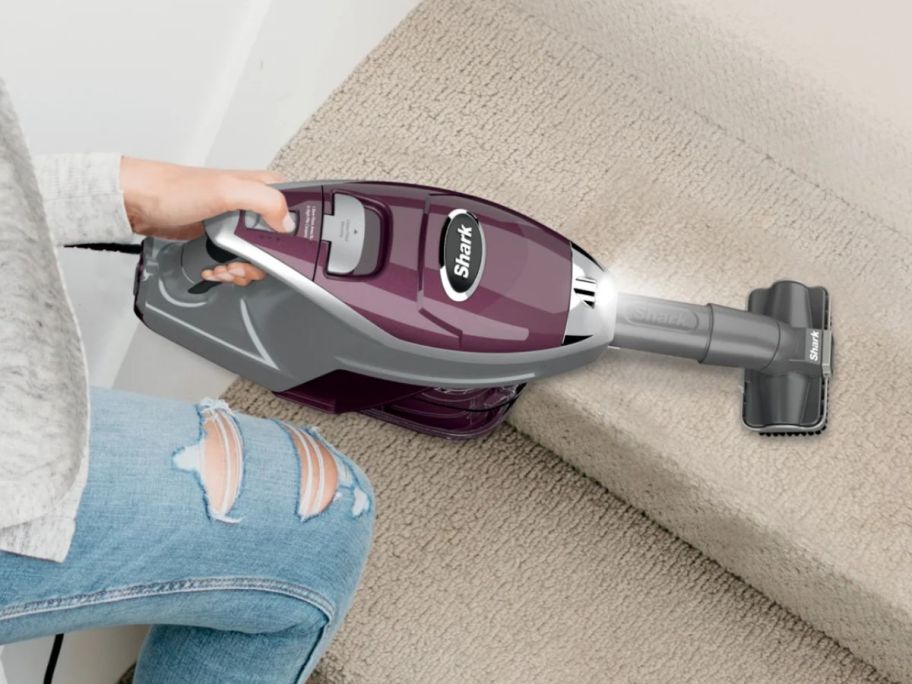 Hand vacuuming stairs with a Shark Rocket Pet Plus Corded Stick Vacuum with the brush attachment