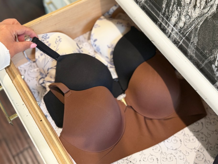 hand grabbing bras from a dresser drawer