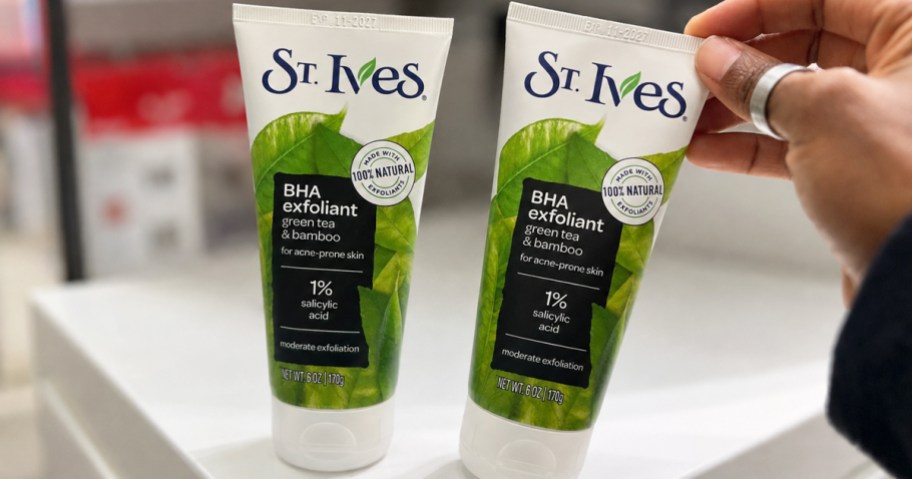 hand touching two bottles of St. Ives Face Scrub in store