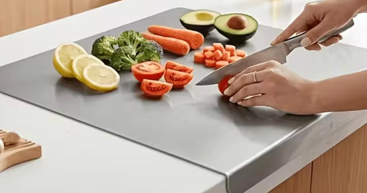 Hand, cutting vegetables and fruit on stainless steel cutting board in kitchen