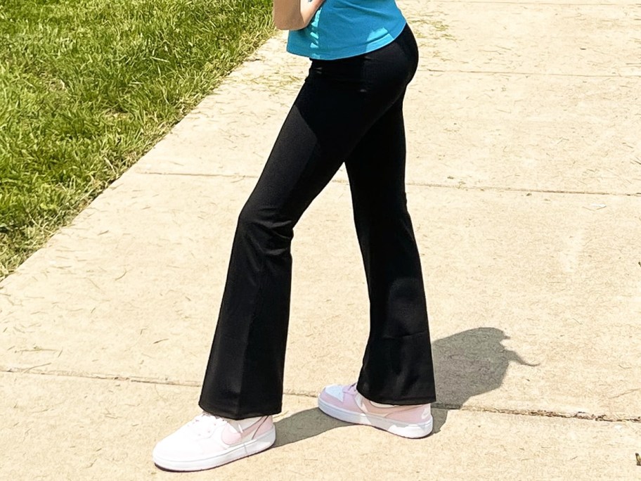 girl wearing black flare leggings and white puma sneakers