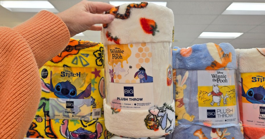 hand holding up a disney print throw blanket in store