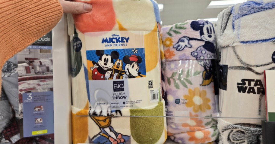 hand reaching for disney throw blankets on store shelf