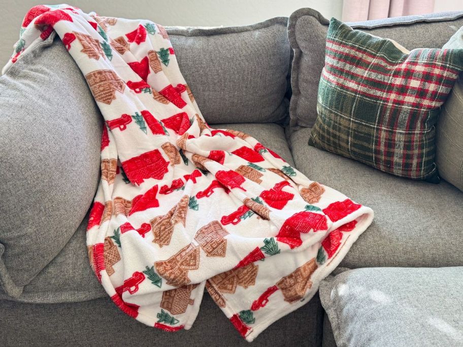 The Big One Holiday Throw with Gingerbread Houses and Red Trucks on a gray couch