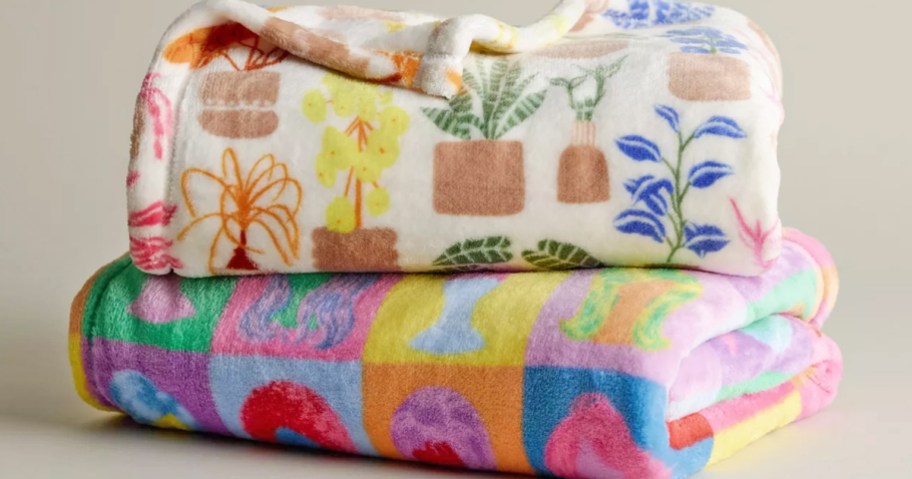 two rainbow print throw blankets folded and stacked on one another