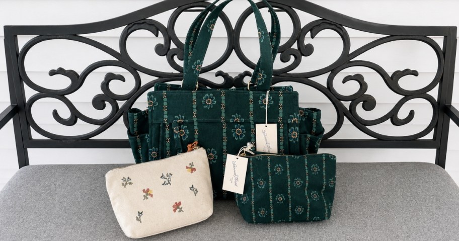 universal thread brand green floral printed tote bag sitting outside on bench with matching zippered pouches