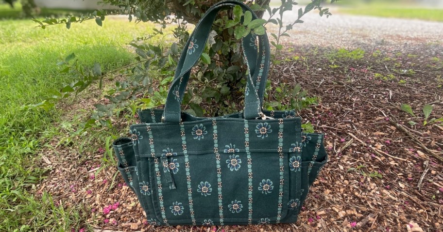 universal thread brand green floral printed tote bag sitting outside on mulch