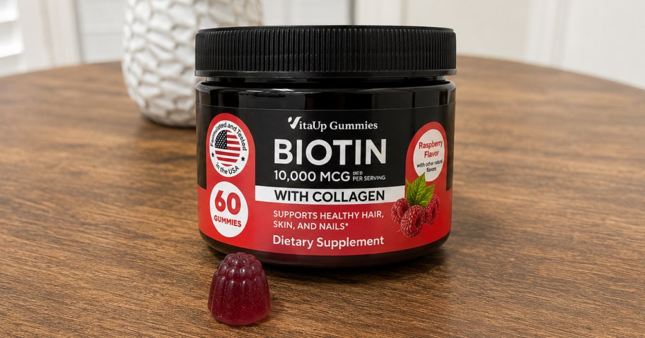 VitaUp Biotin Gummies jar on table with a single gummy in front of it