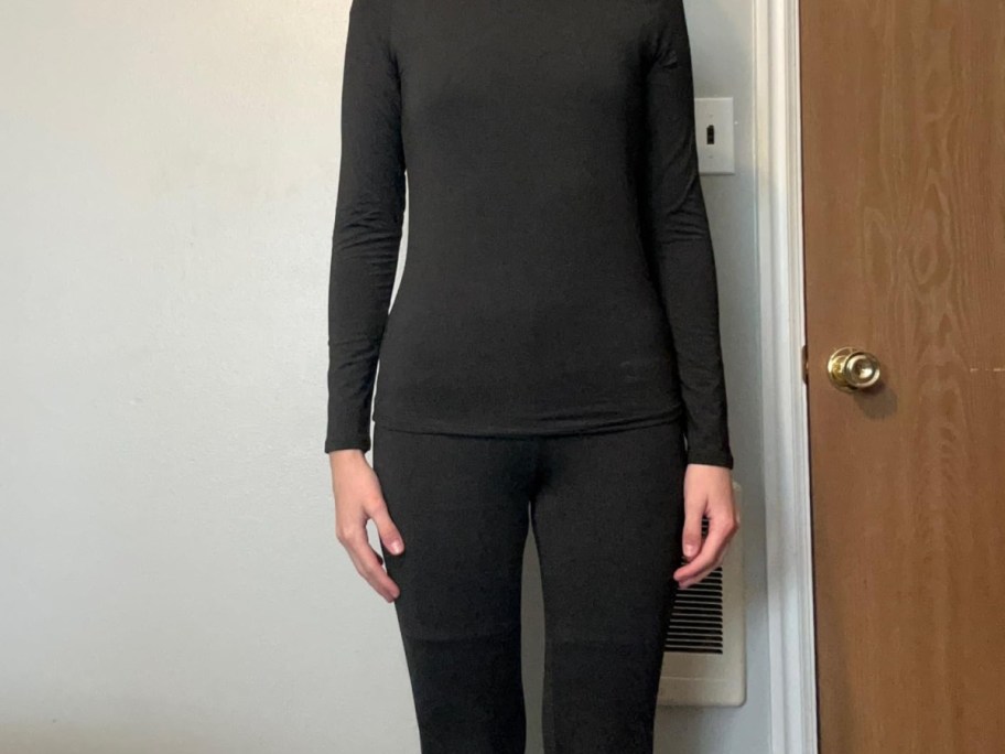 A person wearing a black long-sleeve thermal top and matching thermal leggings.