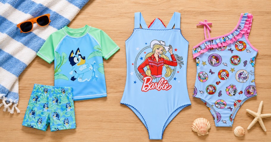 Bluey, Rodeo Barbie and character kids swimsuits arranged with poolside accessories.