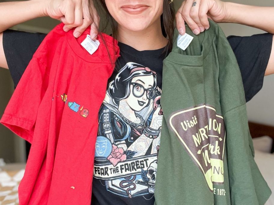 A woman holding up 2 woot graphic tees