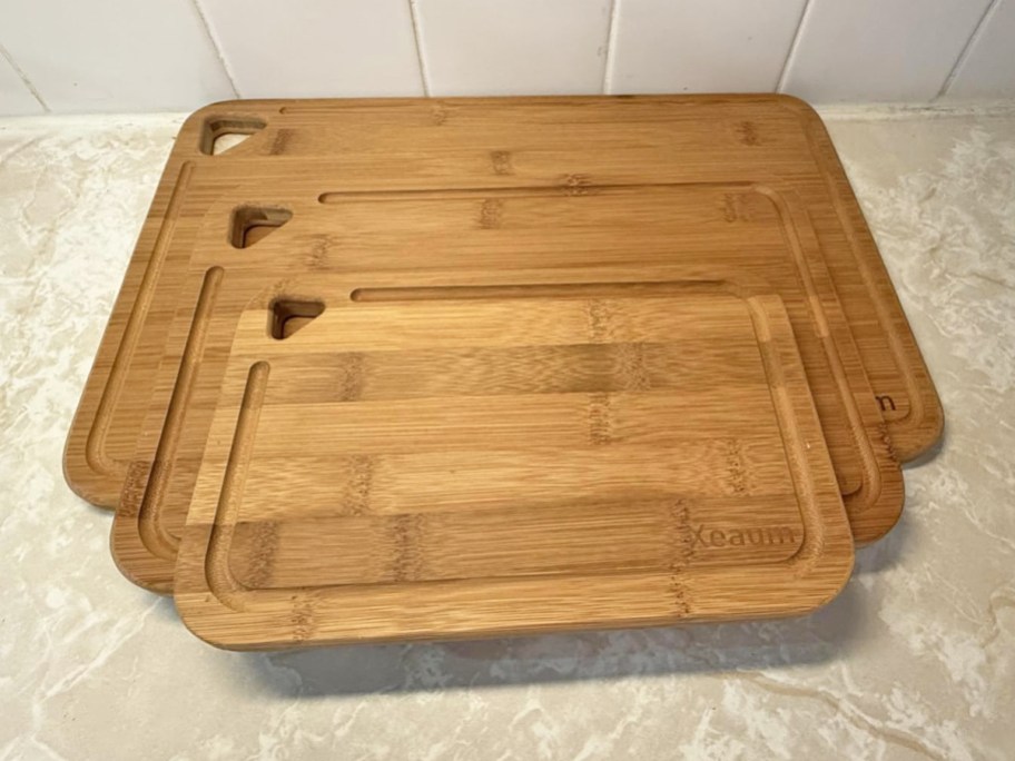3 bamboo cutting boards stacked on a counter