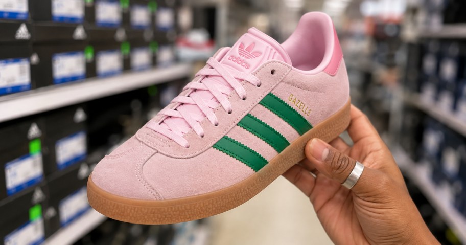 hand holding up a pink and green adidas shoe in store