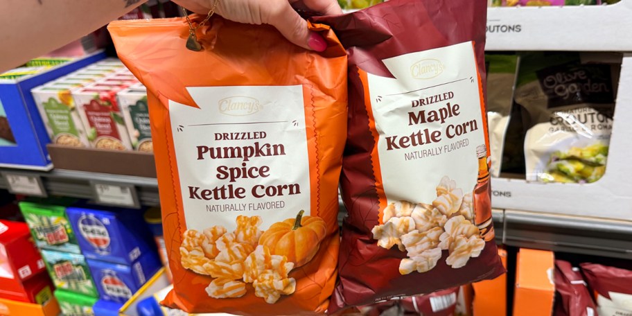 hand holding two bags of kettle corn 