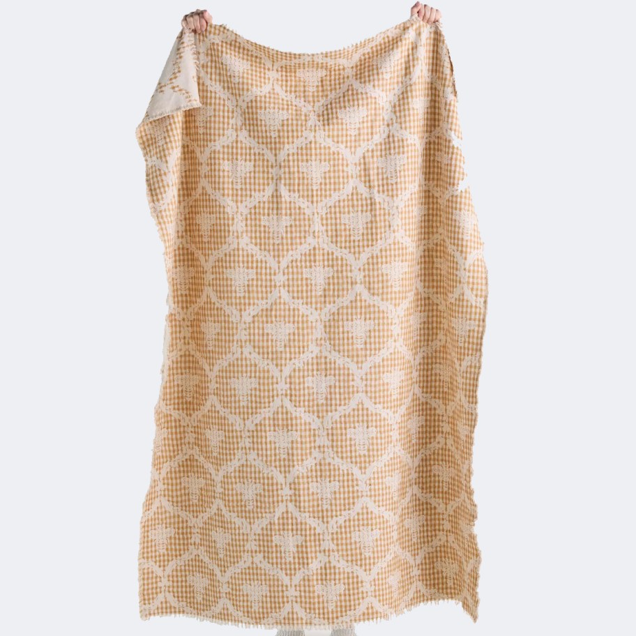 person holding up yellow bee blanket 