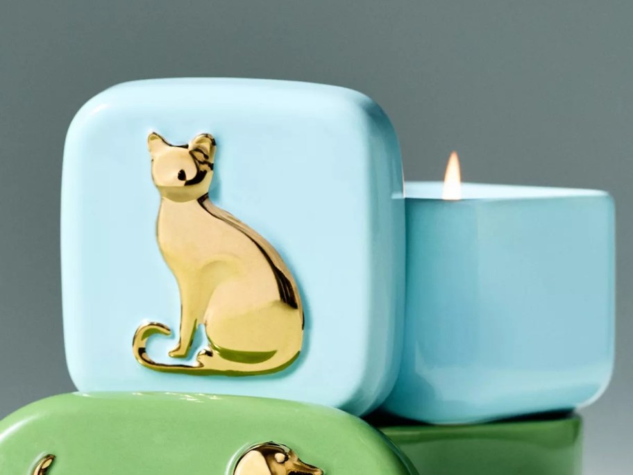 a ceramic candle with a gold cat on the lid