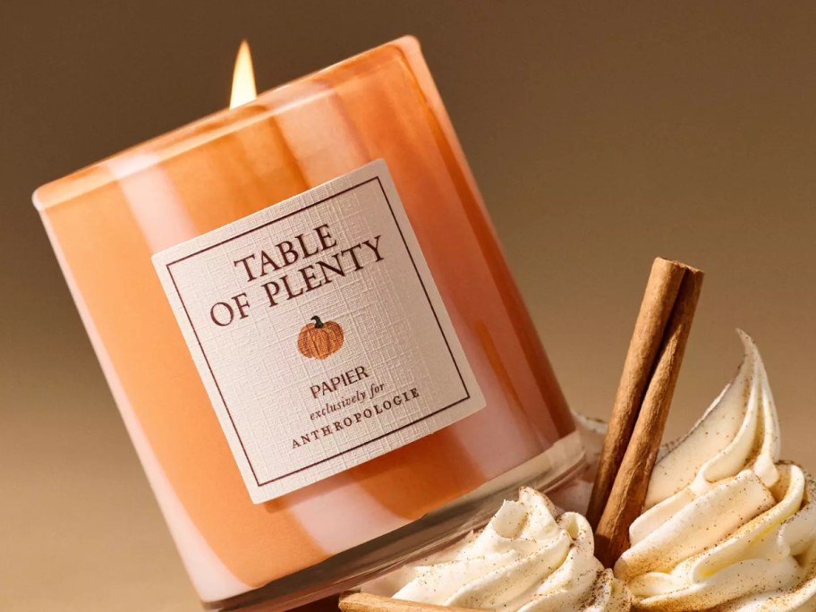 an orange striped candle next to fall items