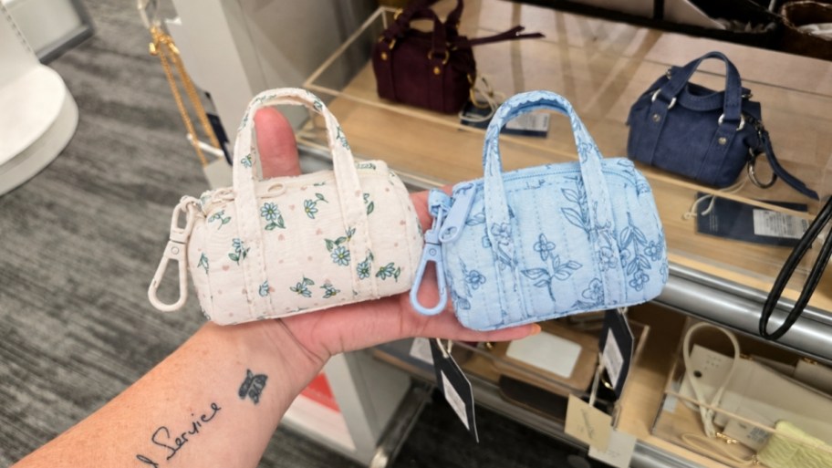 womans hand holding two mini bag charms