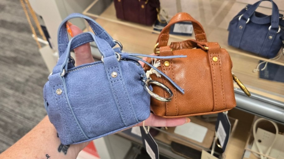 womans hand holding two mini bag charms