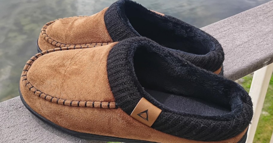pair of brown men's slippers on a deck railing