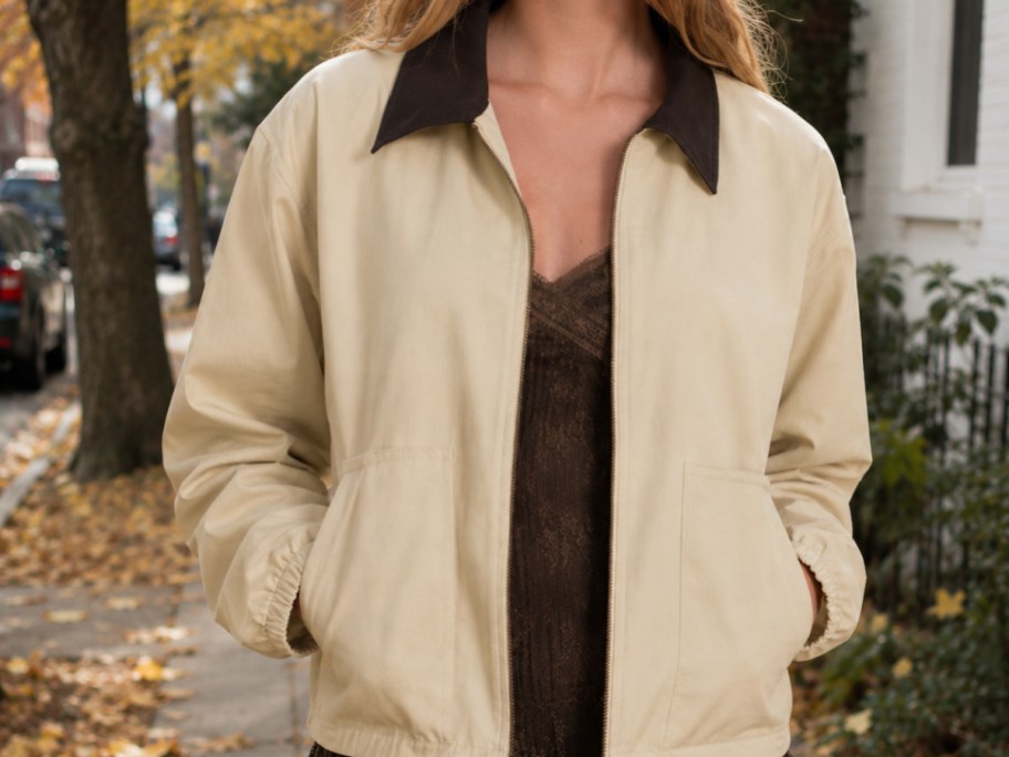 woman wearing a cream barn jacket walking down a city street in the fall