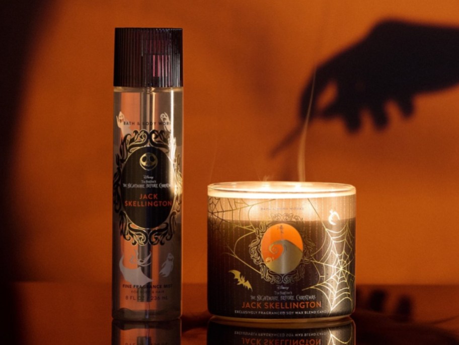 shadow of a hand lighting a candle on an orange background