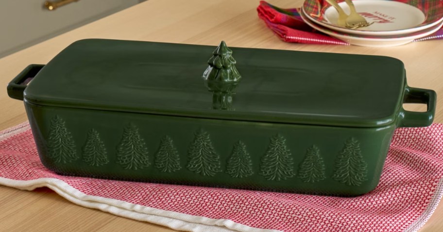 a rectangle green baking dish with a lid that has a Christmas tree finial on it