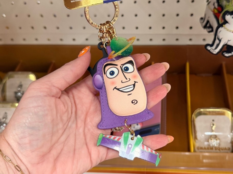 womans hand holding a buzz lightyear bag charm