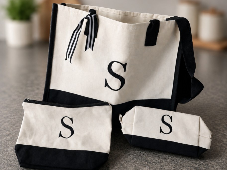 set of three white and black canvas initial bags on a countertop