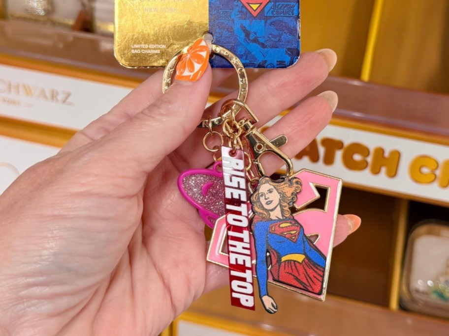 womans hand holding a super girl bag charm