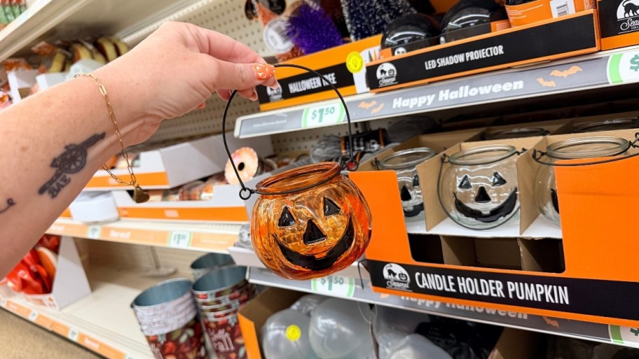 hand holding a glass jack o lantern candle holder
