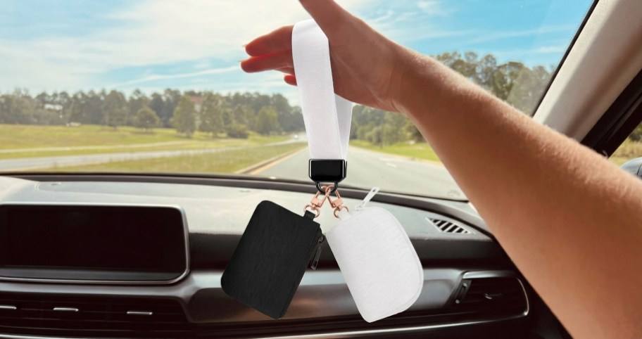 hand holding a black and white dual wristlet in a car